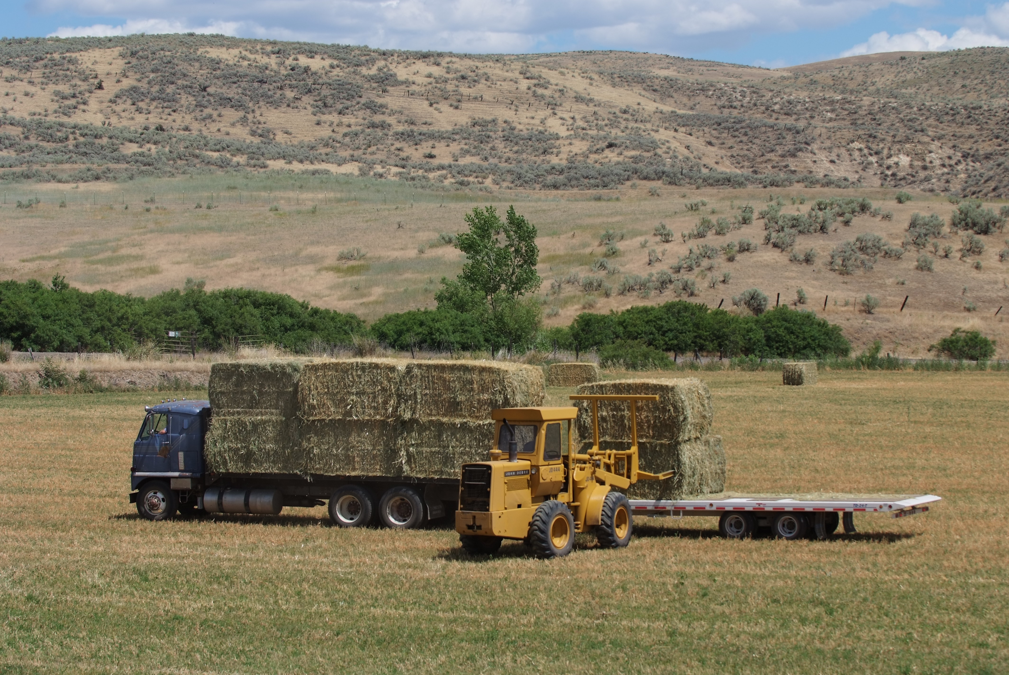 Tractor and truck hauling hay on farm